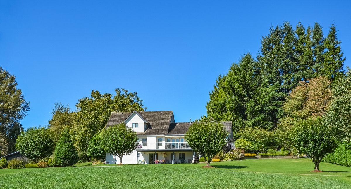 Big family house built  on farm land. Residential house with big green lawn in front on sunny day in British Columbia